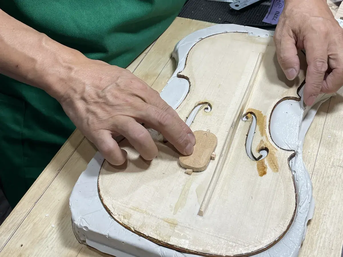 A Bosky Strings luthier fitting the top of a violin at the workbench